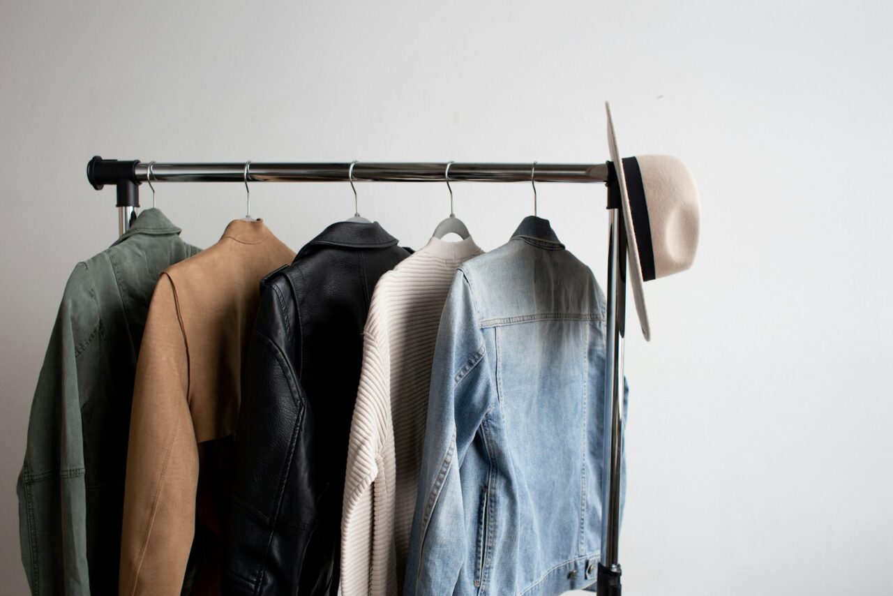Minimalist clothing rack with neutral-colored timeless wardrobe basics on wooden hangers