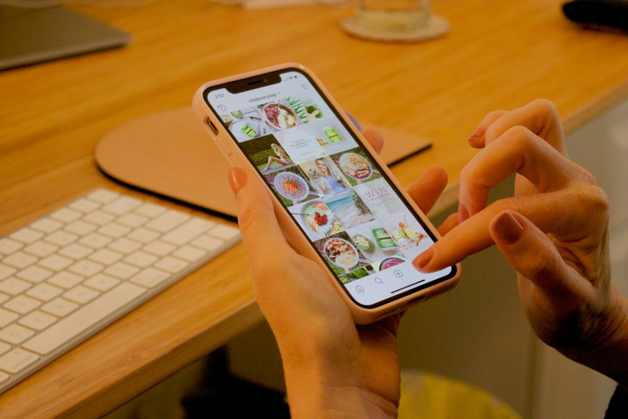 Person holding a smartphone and scrolling through a social media feed