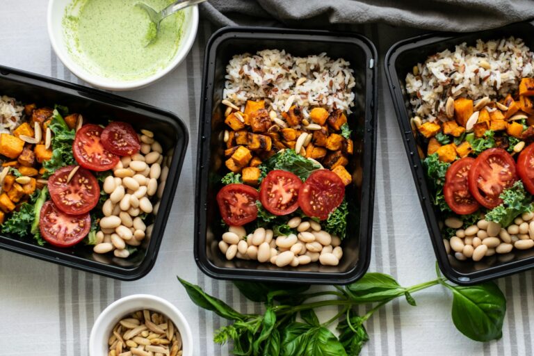 Glass meal prep containers filled with rice, roasted vegetables, and chicken on a kitchen counter