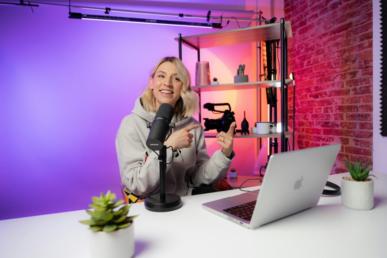 A content creator filming a video at a desk with a ring light and camera