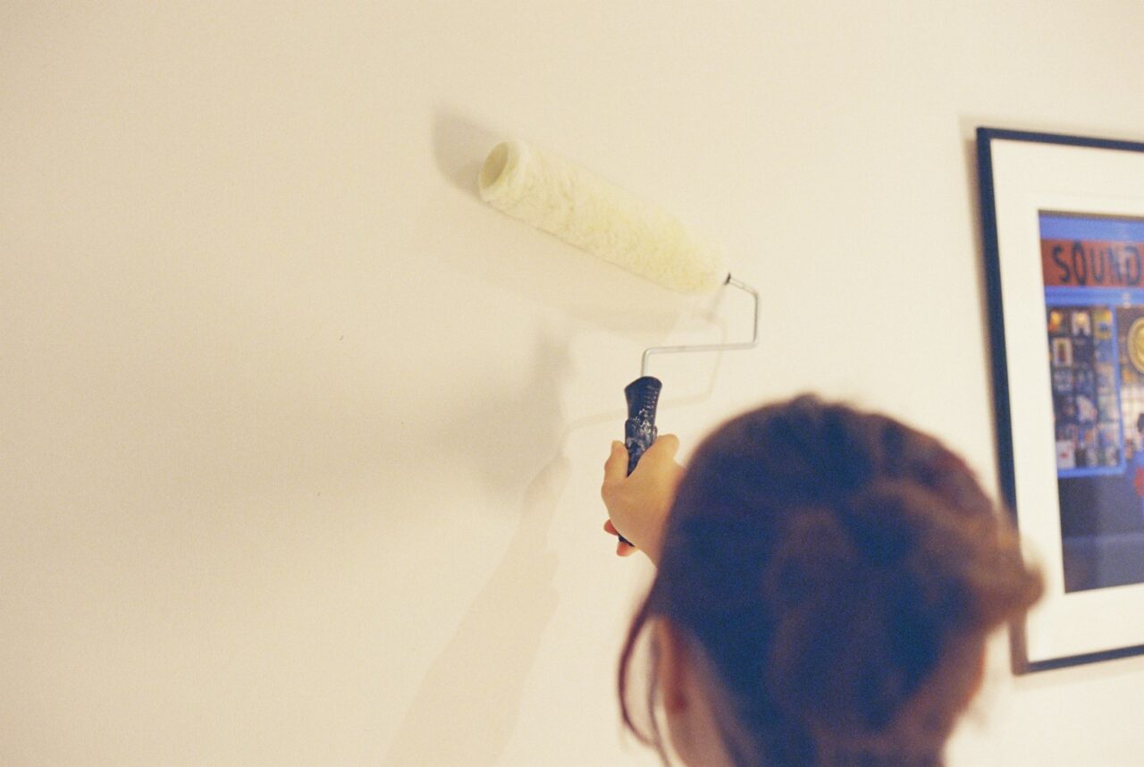 Person painting a living room wall in a fresh neutral color as an affordable home upgrade